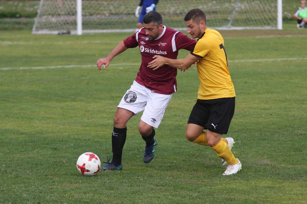 Two soccer players competing for the ball on a grass pitch
