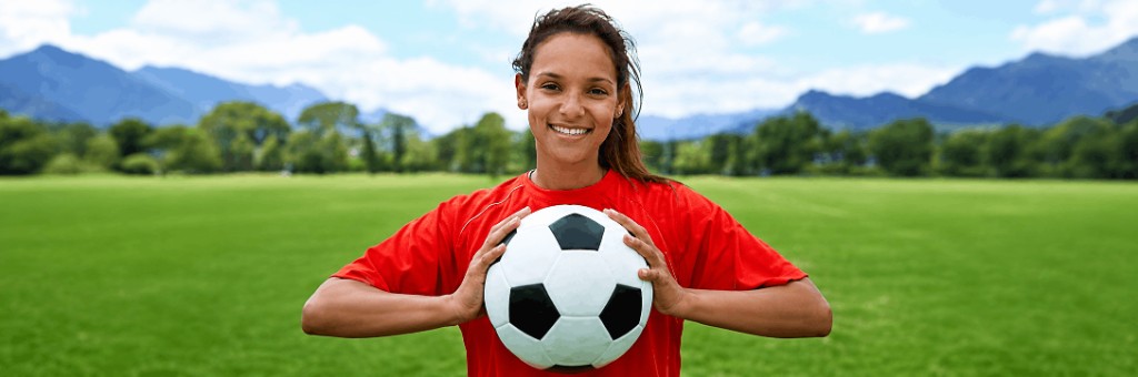 Player holding a soccer ball on a grass field